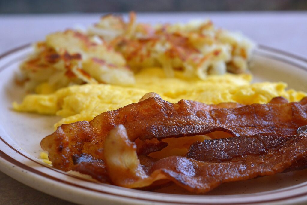 Crispy air-fried bacon strips on a plate with eggs and hash browns